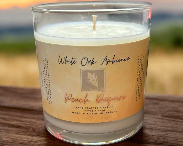 White Oak Ambience Peach Daiquiri coy candle in a clear glass jar with white wax and label, luxury scented wax for home fragrance.