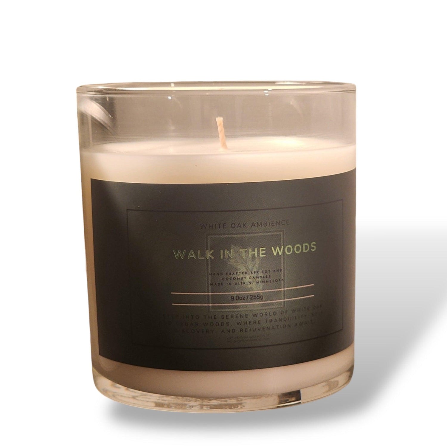 A Walk in the Woods scented candle with a single wick, housed in an amber glass jar with a wooden lid and a black label.